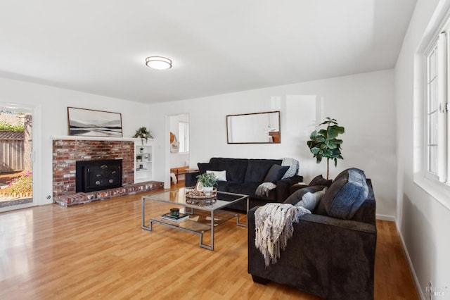 living room with a brick fireplace, wood finished floors, and baseboards