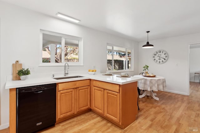 kitchen featuring light wood-type flooring, light countertops, dishwasher, and a sink