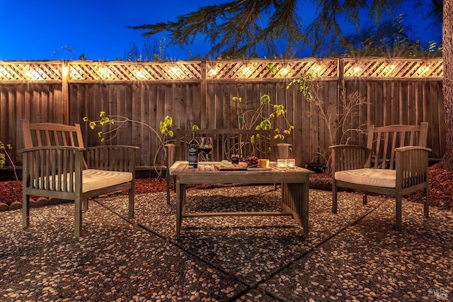 patio at night featuring a fenced backyard