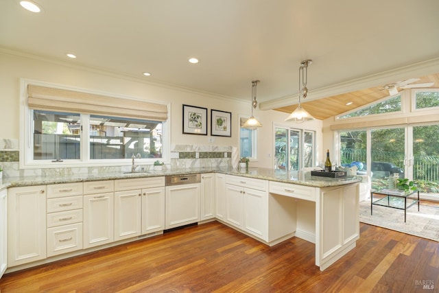 kitchen with light stone counters, decorative light fixtures, crown molding, a sink, and a peninsula