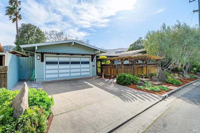 view of front of property featuring an attached garage, fence, and concrete driveway