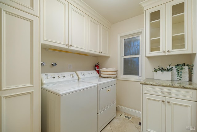 laundry area featuring light tile patterned floors, cabinet space, visible vents, independent washer and dryer, and baseboards