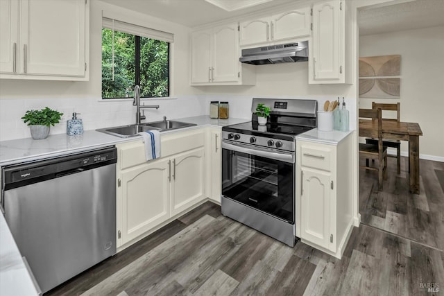 kitchen featuring stainless steel appliances, a sink, dark wood finished floors, and under cabinet range hood