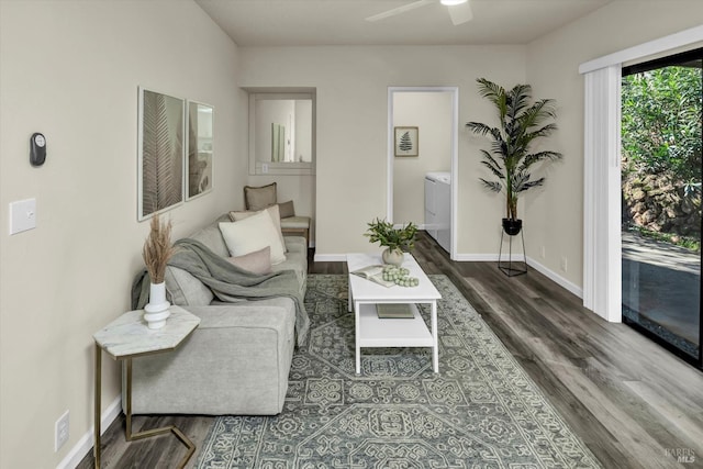 living room with a ceiling fan, baseboards, washer and dryer, and wood finished floors