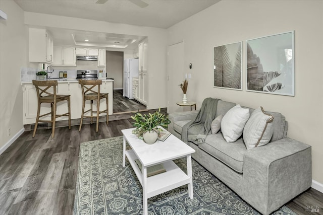 living room featuring ceiling fan, dark wood-style flooring, and baseboards