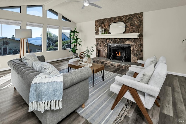 living area with baseboards, a ceiling fan, wood finished floors, vaulted ceiling with beams, and a fireplace