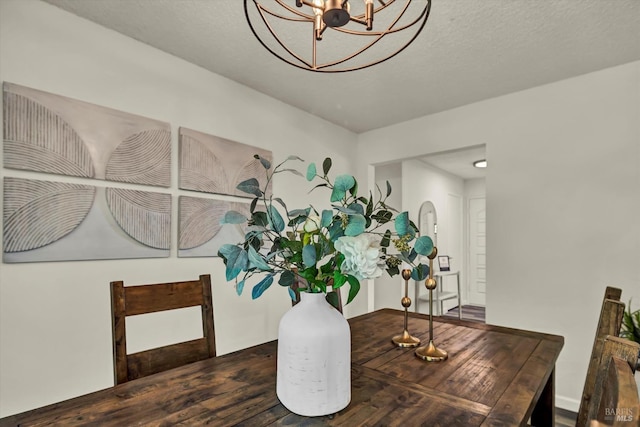 dining space with a chandelier, a textured ceiling, and wood finished floors