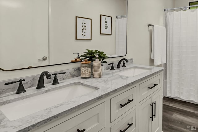 full bath with double vanity, a sink, and wood finished floors