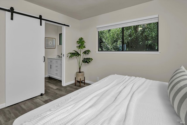 bedroom featuring dark wood-style floors, a barn door, and baseboards