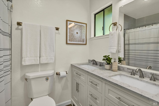 bathroom featuring toilet, double vanity, baseboards, and a sink