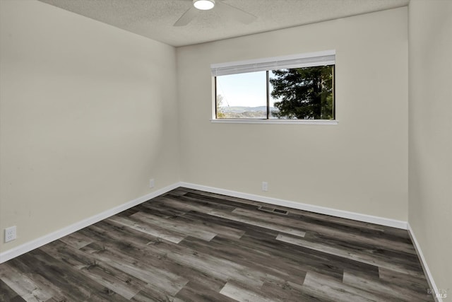 empty room with a ceiling fan, dark wood-style flooring, a textured ceiling, and baseboards