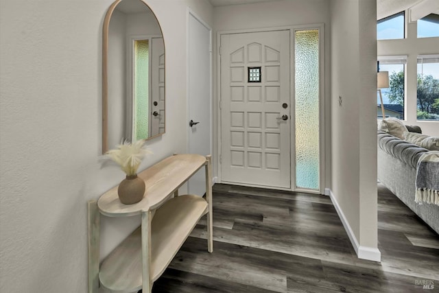 entryway featuring dark wood-type flooring, arched walkways, and baseboards