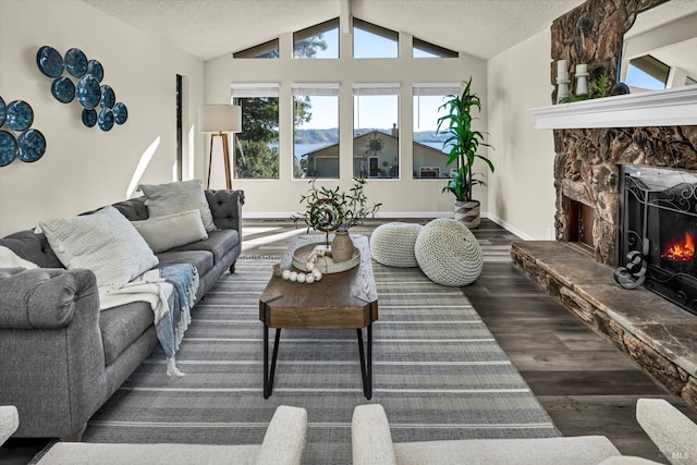 living area with a fireplace, vaulted ceiling, a textured ceiling, and wood finished floors