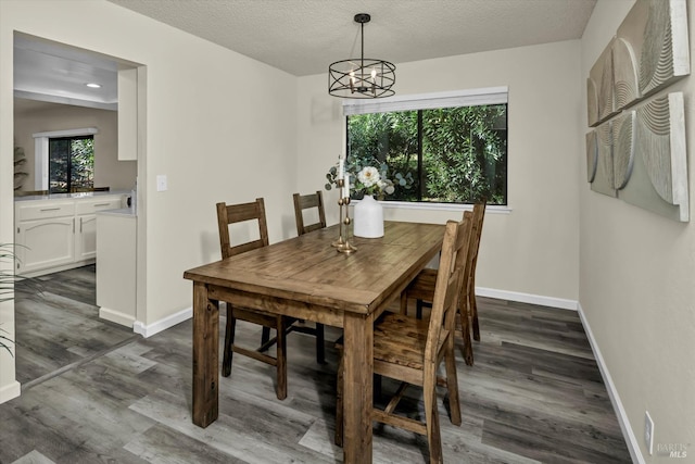 dining area featuring an inviting chandelier, a textured ceiling, baseboards, and dark wood-type flooring