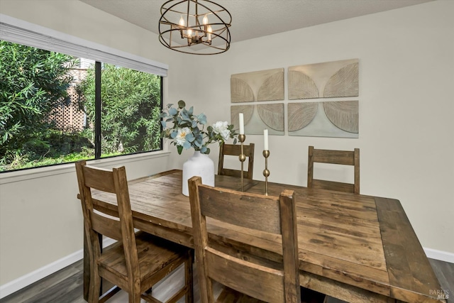 dining space featuring wood finished floors, a textured ceiling, baseboards, and an inviting chandelier