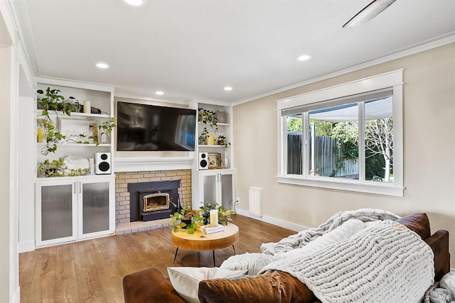 living area with ornamental molding, a fireplace, baseboards, and wood finished floors