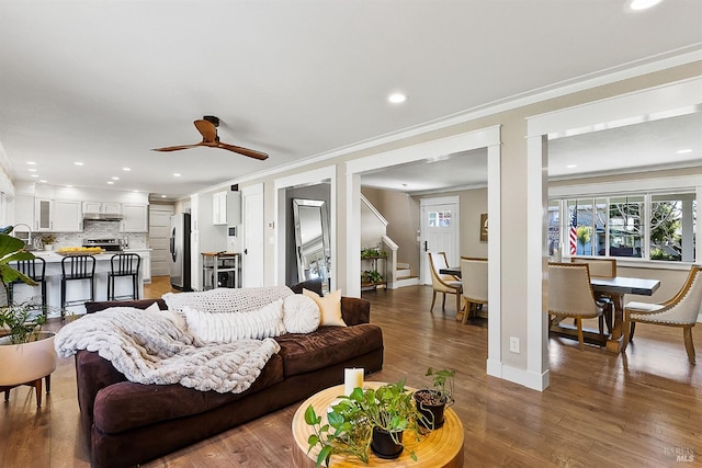 living room with baseboards, ornamental molding, wood finished floors, stairs, and recessed lighting