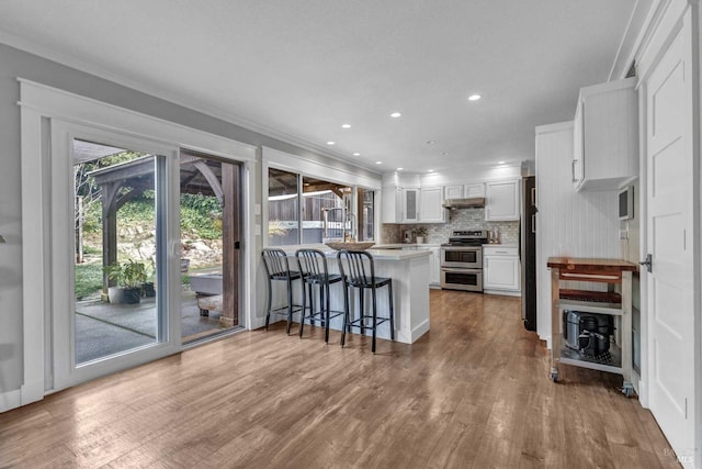 kitchen with decorative backsplash, freestanding refrigerator, a peninsula, double oven range, and white cabinetry