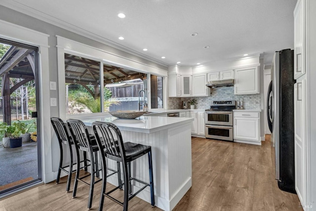 kitchen with stainless steel appliances, white cabinetry, a peninsula, and tasteful backsplash