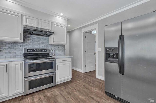 kitchen featuring under cabinet range hood, white cabinets, ornamental molding, appliances with stainless steel finishes, and decorative backsplash