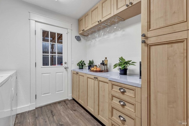 interior space featuring light countertops, light brown cabinetry, wood finished floors, washer and dryer, and baseboards