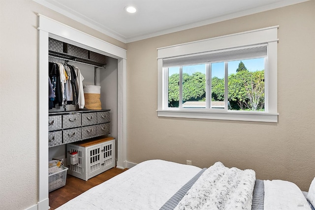 bedroom with crown molding, a closet, wood finished floors, and baseboards