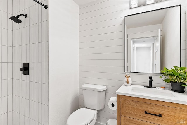 bathroom featuring toilet, tiled shower, and vanity