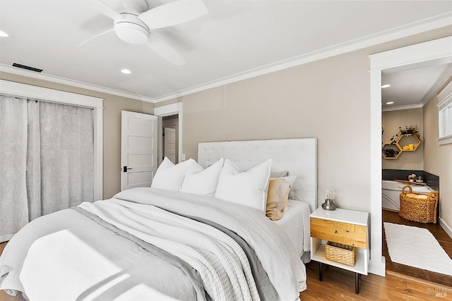 bedroom with a ceiling fan, wood finished floors, visible vents, and crown molding