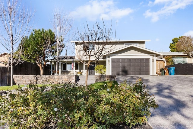 view of front of property featuring a garage, driveway, fence, and stucco siding