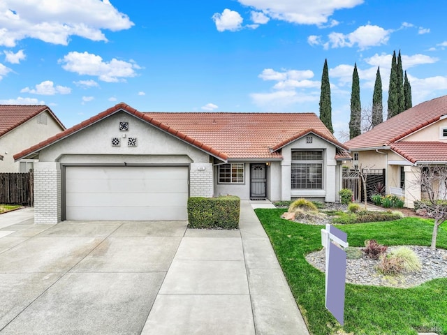 mediterranean / spanish-style house with a tile roof, fence, concrete driveway, a front yard, and a garage