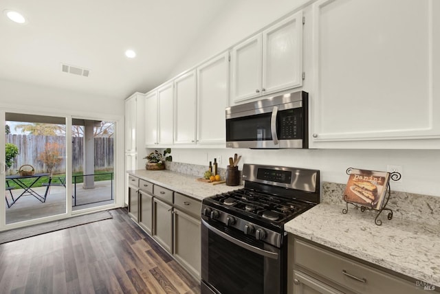 kitchen featuring dark wood finished floors, visible vents, appliances with stainless steel finishes, and light stone countertops