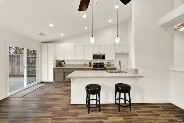 kitchen featuring visible vents, a sink, ceiling fan, stainless steel appliances, and a kitchen bar