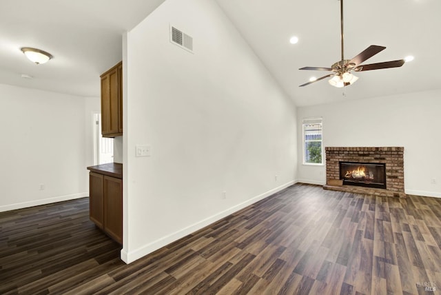 unfurnished living room featuring dark wood-type flooring, a brick fireplace, baseboards, and visible vents