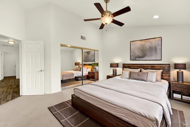 carpeted bedroom featuring a ceiling fan, visible vents, a closet, and high vaulted ceiling