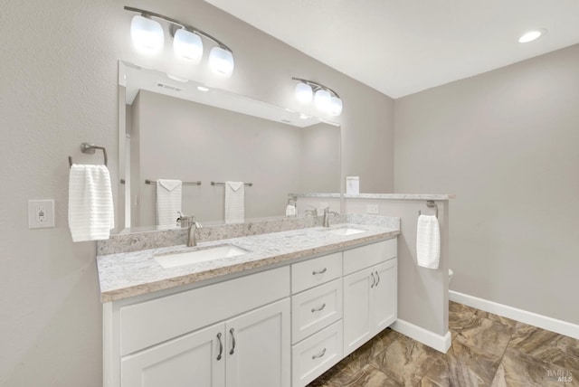 bathroom featuring a sink, visible vents, baseboards, and double vanity