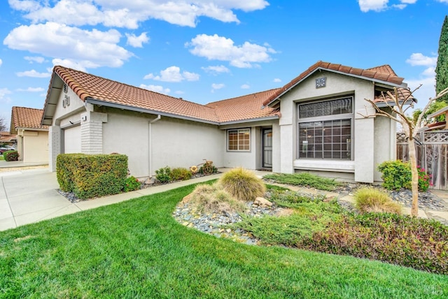 mediterranean / spanish-style home with stucco siding, a front yard, an attached garage, and a tile roof