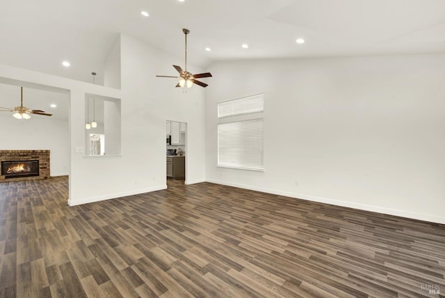 unfurnished living room with dark wood-type flooring, a brick fireplace, a ceiling fan, and high vaulted ceiling