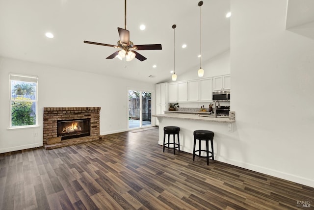 kitchen featuring a breakfast bar, stainless steel microwave, white cabinets, and a healthy amount of sunlight