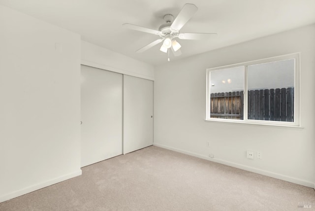 unfurnished bedroom with a ceiling fan, baseboards, a closet, and light carpet