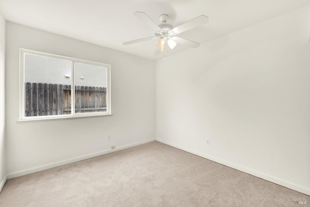 carpeted empty room with a ceiling fan and baseboards