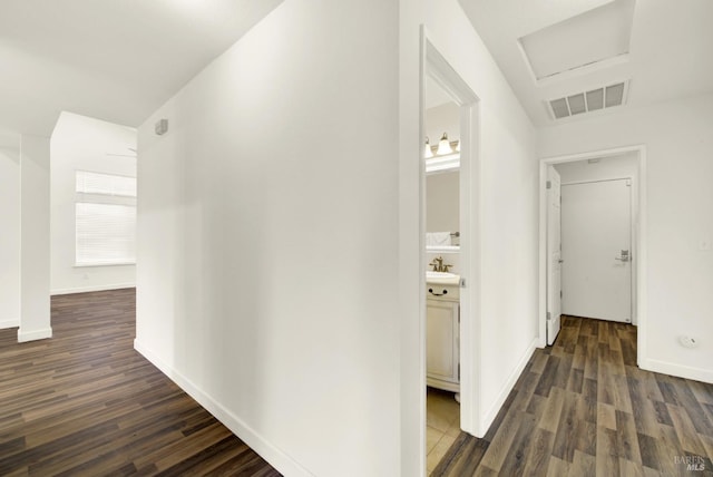 hallway featuring attic access, visible vents, dark wood-style flooring, and a sink