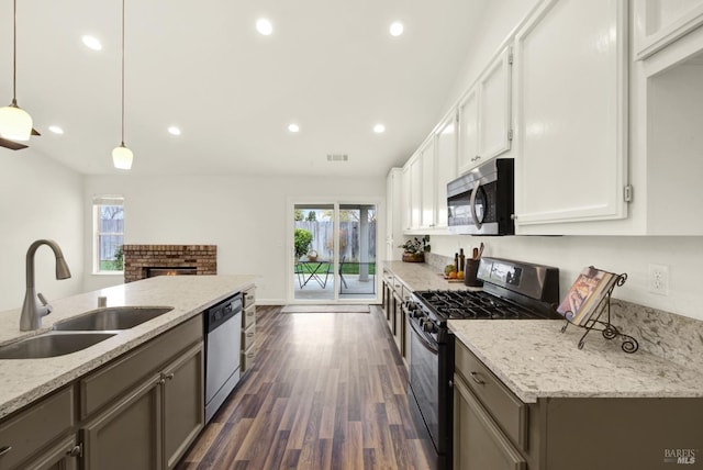 kitchen with dark wood-style floors, visible vents, light stone countertops, a sink, and stainless steel appliances