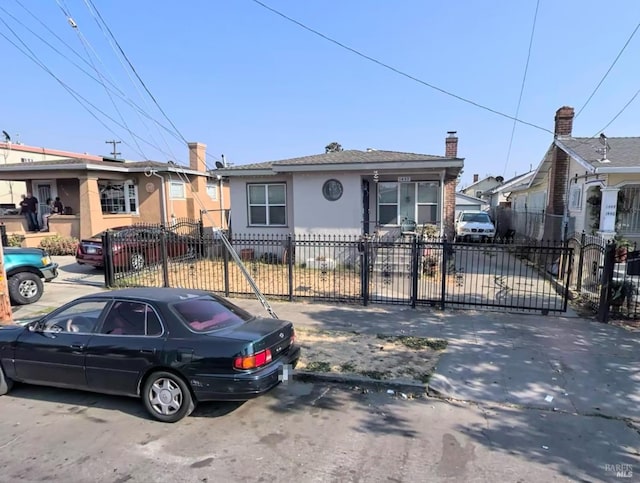 bungalow-style house with a fenced front yard, a gate, and stucco siding