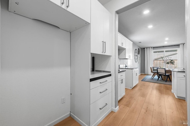 kitchen with baseboards, light wood-type flooring, recessed lighting, white cabinetry, and tasteful backsplash