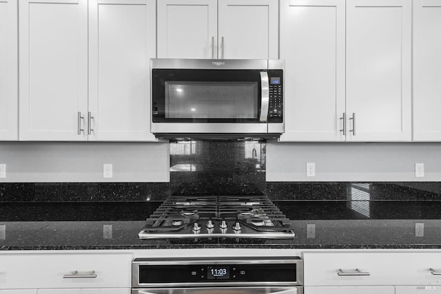 kitchen with white cabinets, appliances with stainless steel finishes, and dark stone countertops