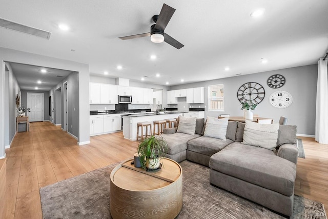 living area featuring light wood-type flooring, visible vents, and recessed lighting