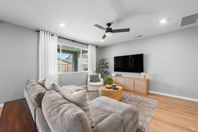 living room featuring visible vents, baseboards, light wood-style floors, and a ceiling fan