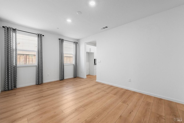 spare room with light wood finished floors, visible vents, baseboards, and a wealth of natural light