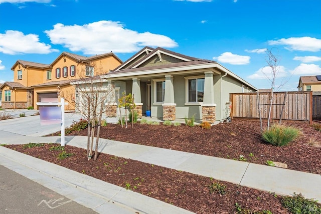 view of front of house with fence, driveway, covered porch, stucco siding, and stone siding