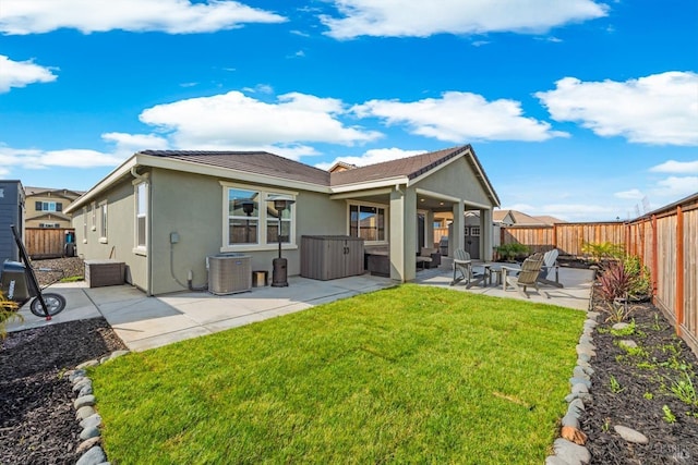 back of house with central AC unit, stucco siding, a yard, a fenced backyard, and a patio area